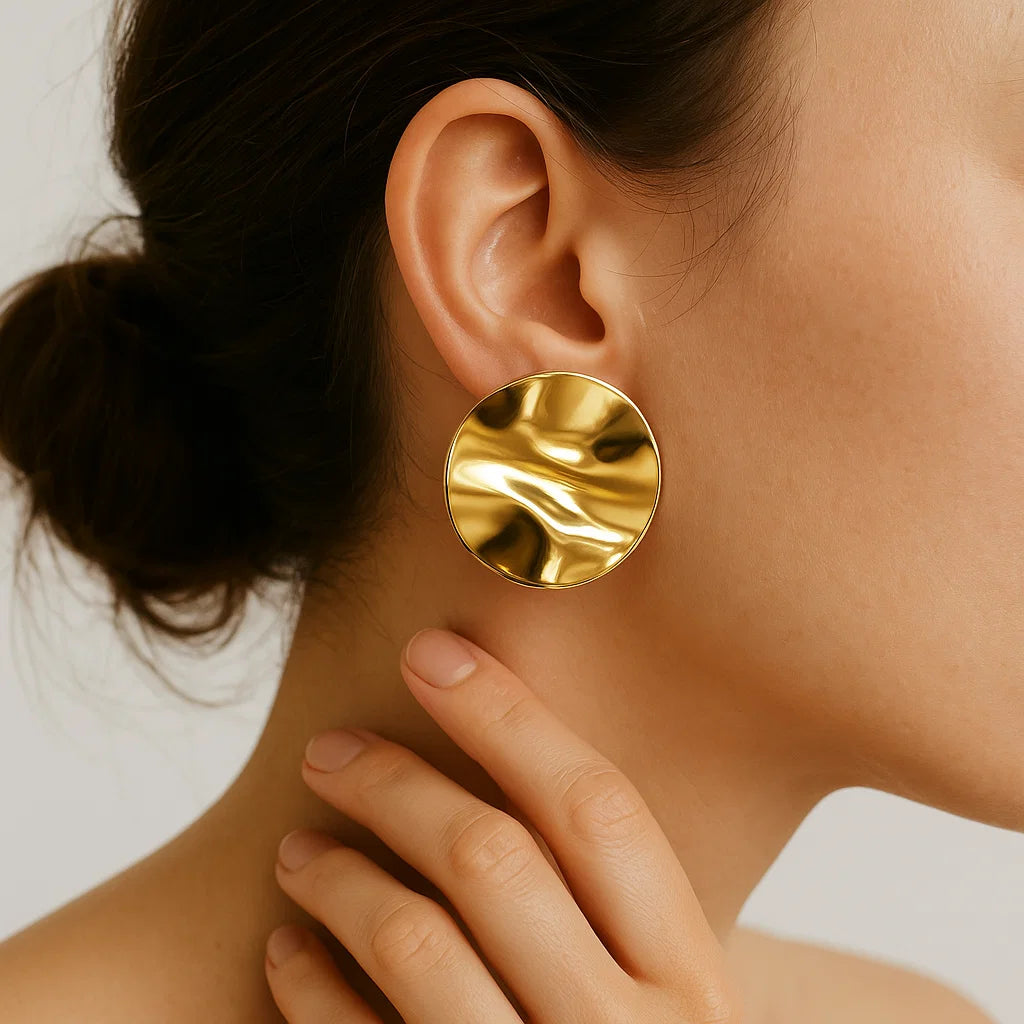 AURUM Golden Mirror 18K
Imagem de brinco circular dourado com superfície espelhada e ondulações suaves, sobre fundo claro.