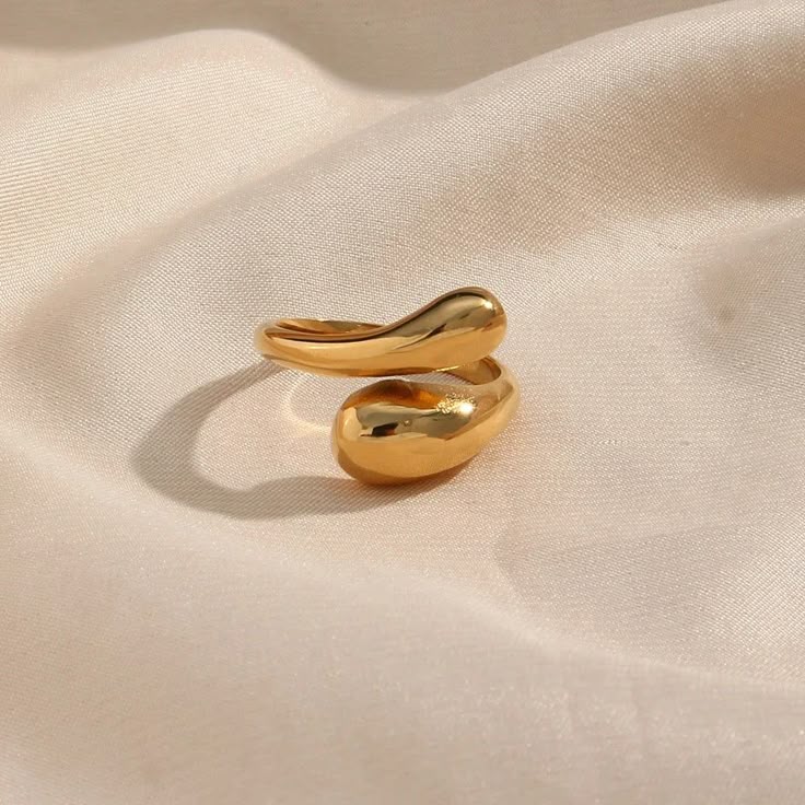 Anel Gota 18K em aço cirúrgico banhado a ouro, com design fluido em forma de gota e acabamento polido brilhante, sobre fundo branco minimalista.
