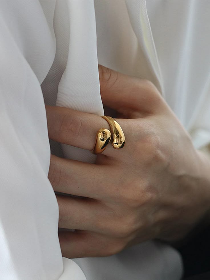 Anel Gota 18K em aço cirúrgico banhado a ouro, com design fluido em forma de gota e acabamento polido brilhante, sobre fundo branco minimalista.