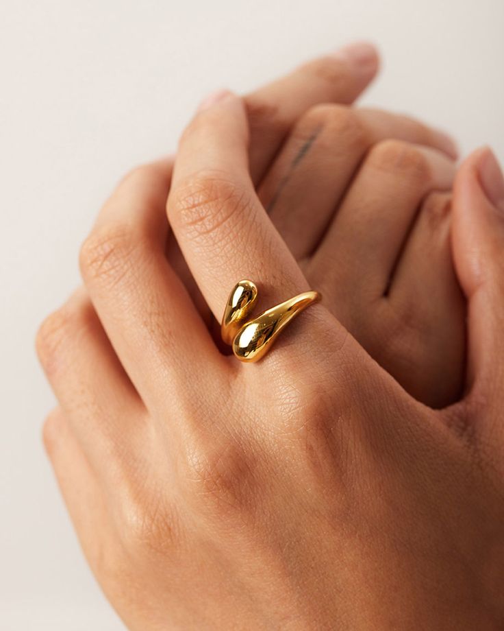 Anel Gota 18K em aço cirúrgico banhado a ouro, com design fluido em forma de gota e acabamento polido brilhante, sobre fundo branco minimalista.
