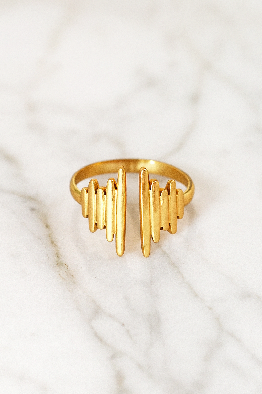 Anel Pulse 18K em aço cirúrgico banhado a ouro, com design moderno formado por filetes verticais de diferentes alturas, lembrando ondas sonoras, fotografado em fundo neutro.