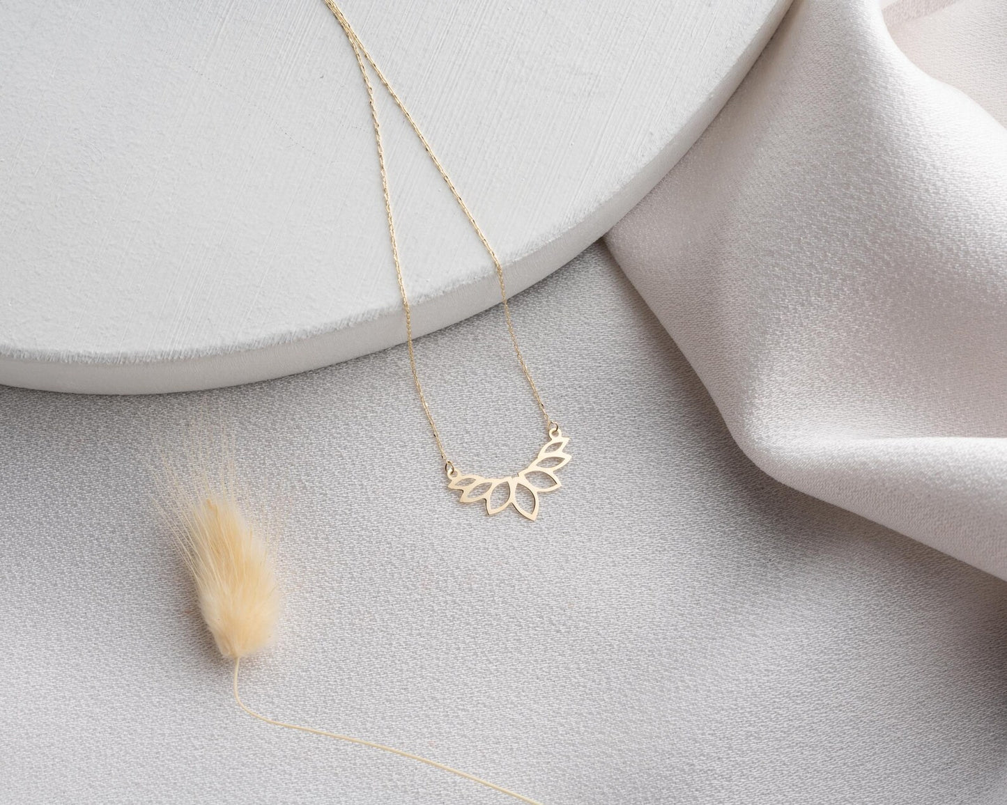 Colar dourado AURUM 18K com corrente fina e pingente delicado em fundo neutro.