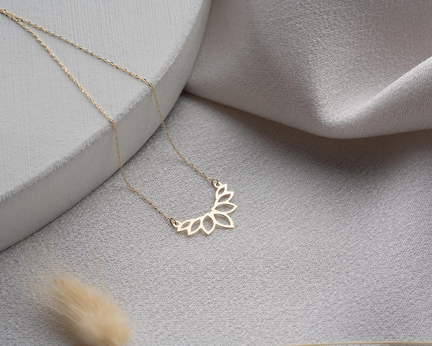 Colar dourado AURUM 18K com corrente fina e pingente delicado em fundo neutro.