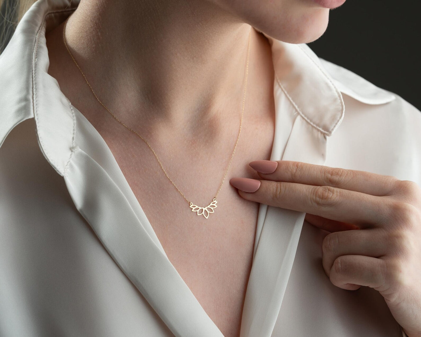 Colar dourado AURUM 18K com corrente fina e pingente delicado em fundo neutro.