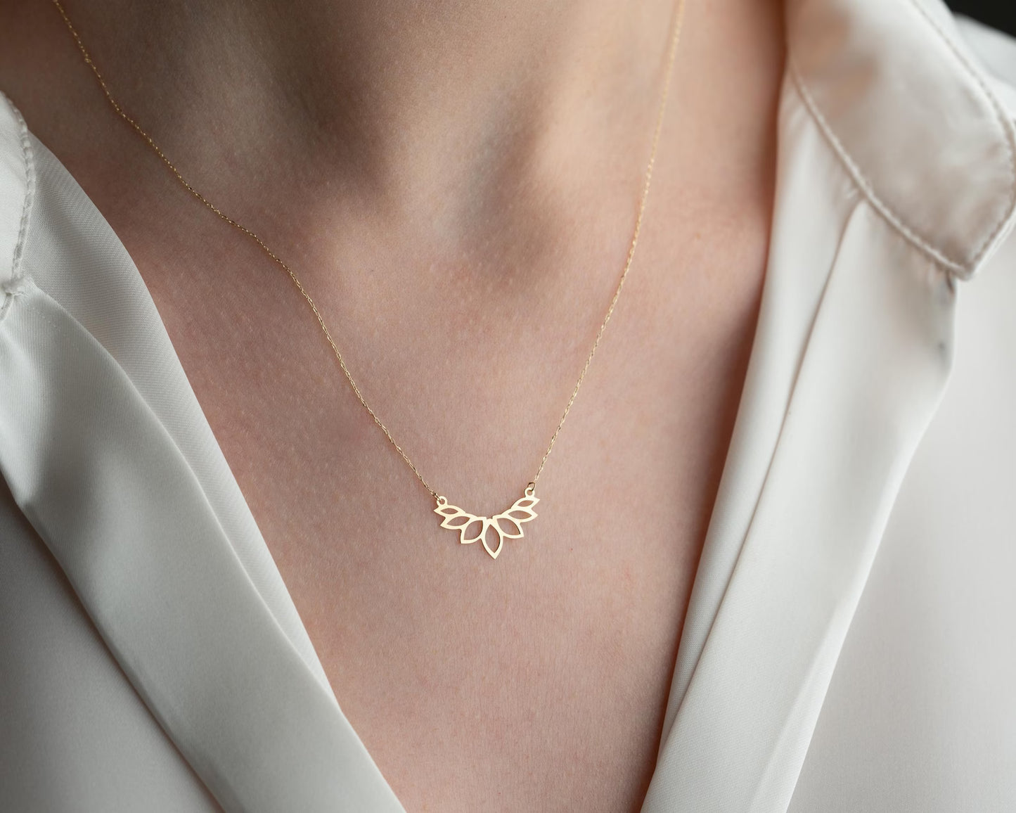 Colar dourado AURUM 18K com corrente fina e pingente delicado em fundo neutro.