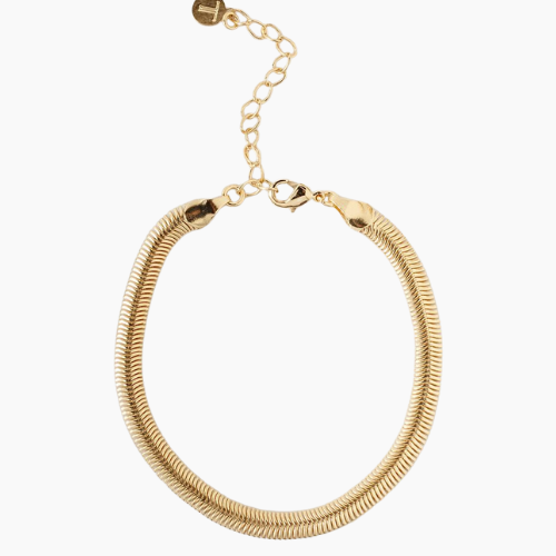 Pulseira dourada com malha flexível estilo "cobra", acabamento brilhante e fecho ajustável com corrente extensora e pingente circular, exibida sobre fundo branco.