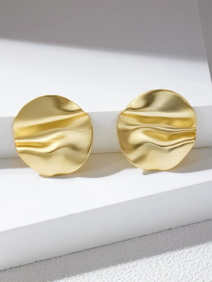 AURUM Golden Mirror 18K
Imagem de brinco circular dourado com superfície espelhada e ondulações suaves, sobre fundo claro.