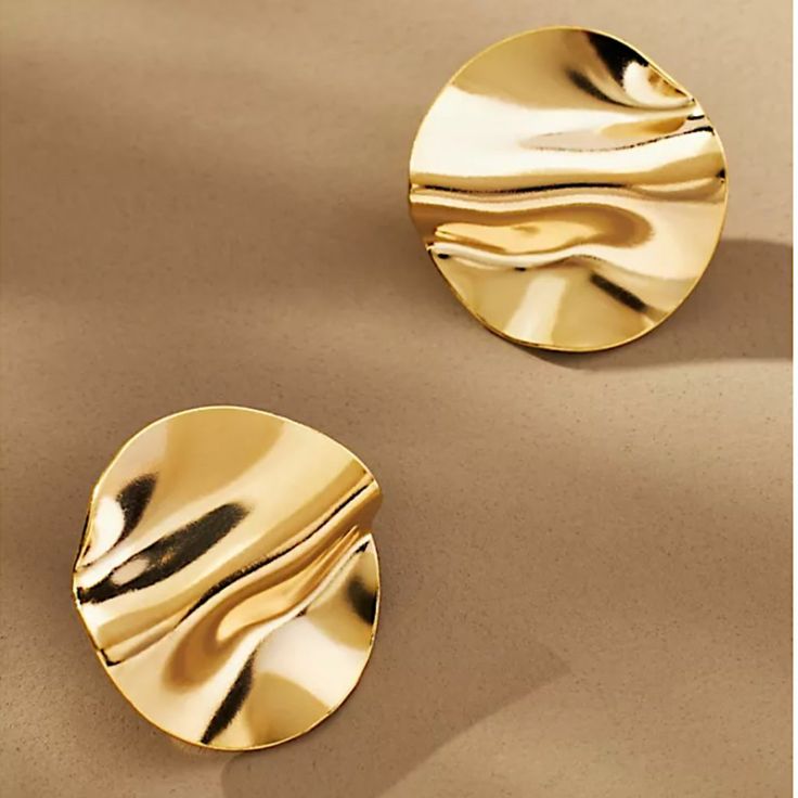 AURUM Golden Mirror 18K
Imagem de brinco circular dourado com superfície espelhada e ondulações suaves, sobre fundo claro.