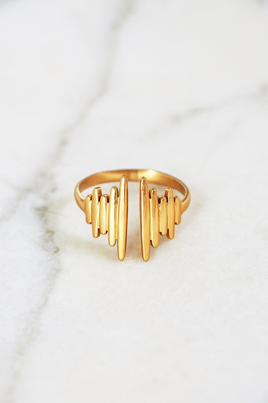 Anel Pulse 18K em aço cirúrgico banhado a ouro, com design moderno formado por filetes verticais de diferentes alturas, lembrando ondas sonoras, fotografado em fundo neutro.

