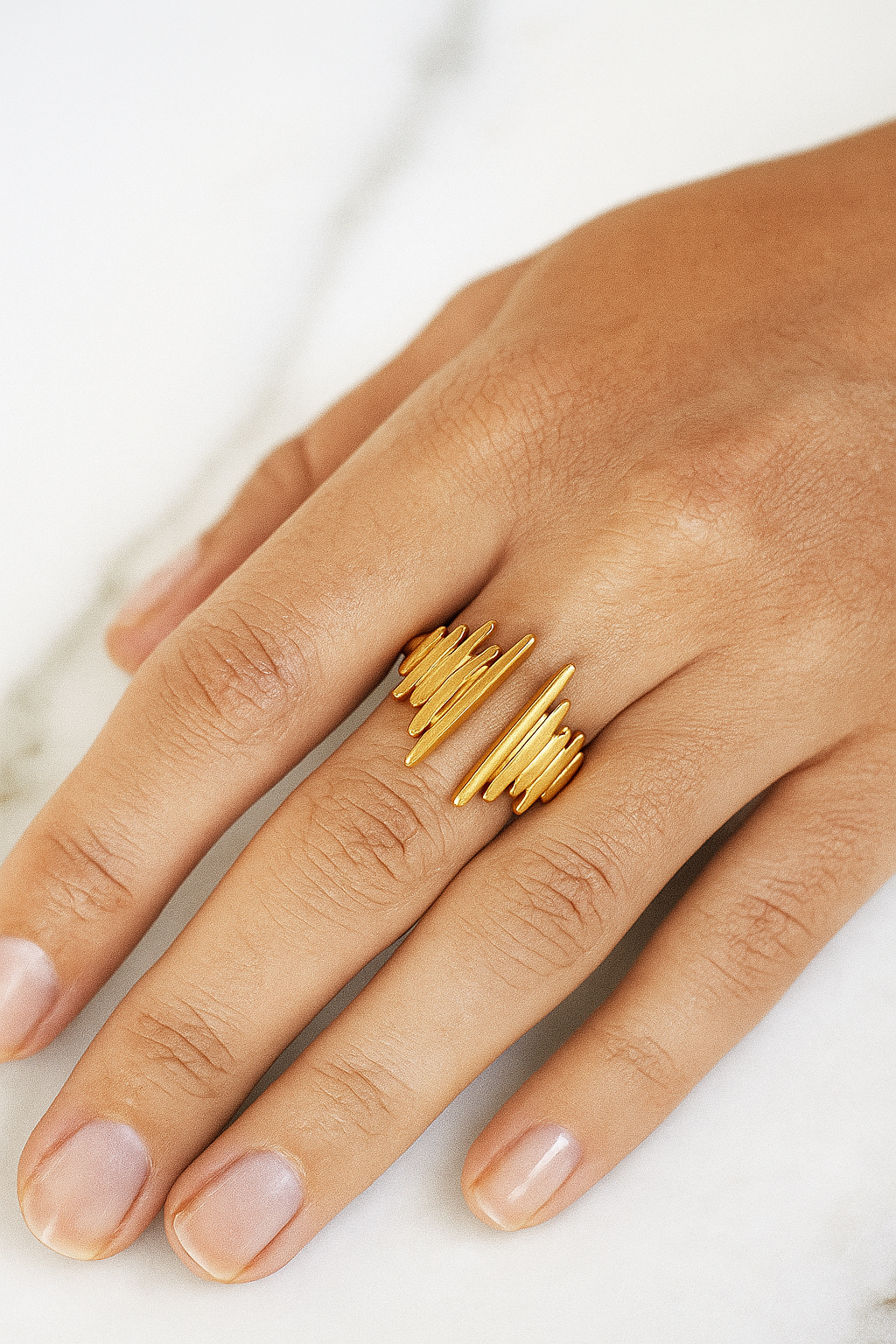 Anel Pulse 18K em aço cirúrgico banhado a ouro, com design moderno formado por filetes verticais de diferentes alturas, lembrando ondas sonoras, fotografado em fundo neutro.

