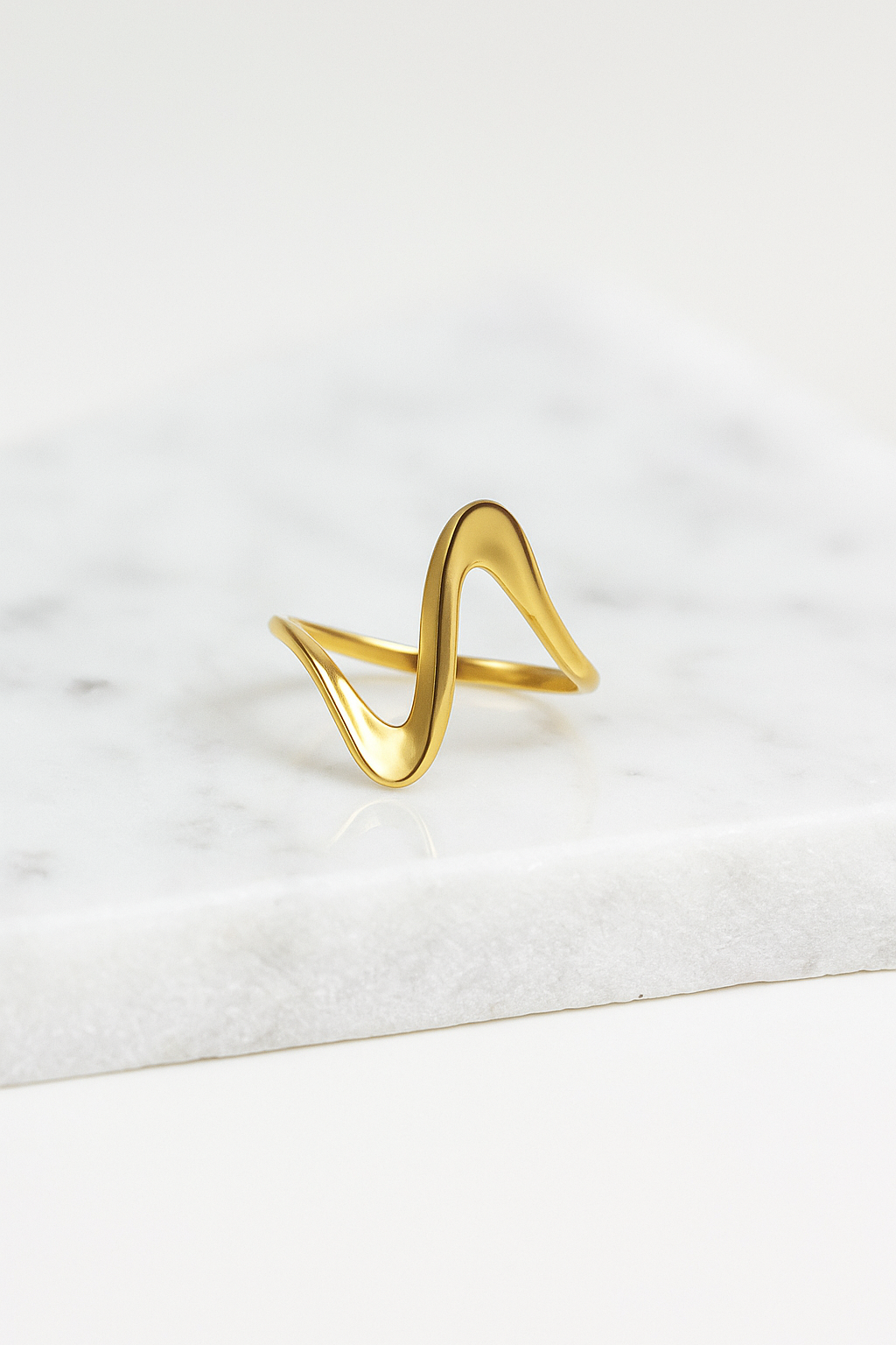 Anel Ripple 18K de aço cirúrgico banhado a ouro com design fino, ondulado e polido, formando curvas suaves e elegantes.