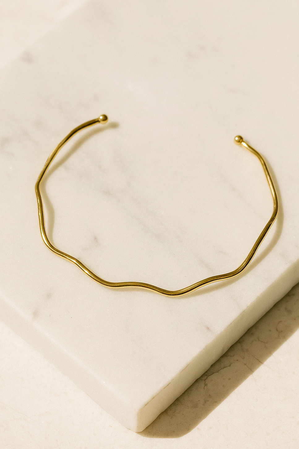 Colar AURUM Halo 18K em aço cirúrgico banhado a ouro, com formato ondulado minimalista, fotografado sobre fundo branco.