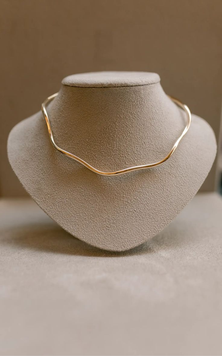 Colar AURUM Halo 18K em aço cirúrgico banhado a ouro, com formato ondulado minimalista, fotografado sobre fundo branco.