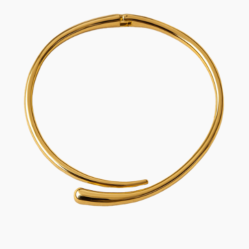 Colar rígido banhado a ouro 18K, com formato de meia-lua aberta e acabamento polido espelhado, posicionado ao redor do pescoço de uma modelo com top preto e fundo bege neutro.