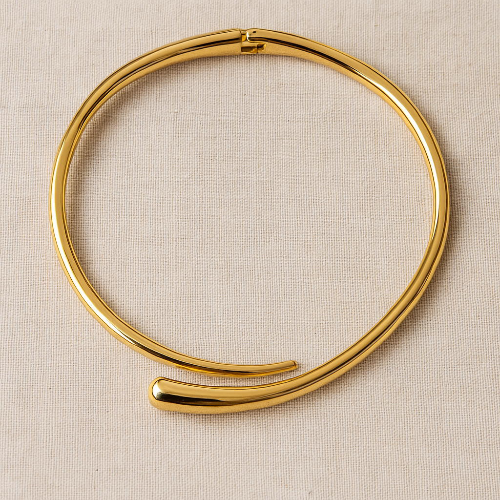 Colar rígido banhado a ouro 18K, com formato de meia-lua aberta e acabamento polido espelhado, posicionado ao redor do pescoço de uma modelo com top preto e fundo bege neutro.